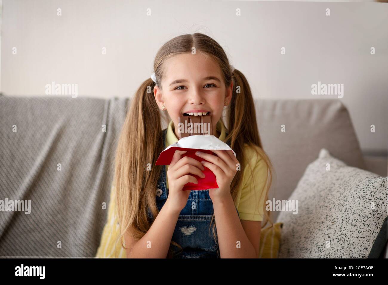 Lady eating chocolate sitting on a couch at home Stock Photo