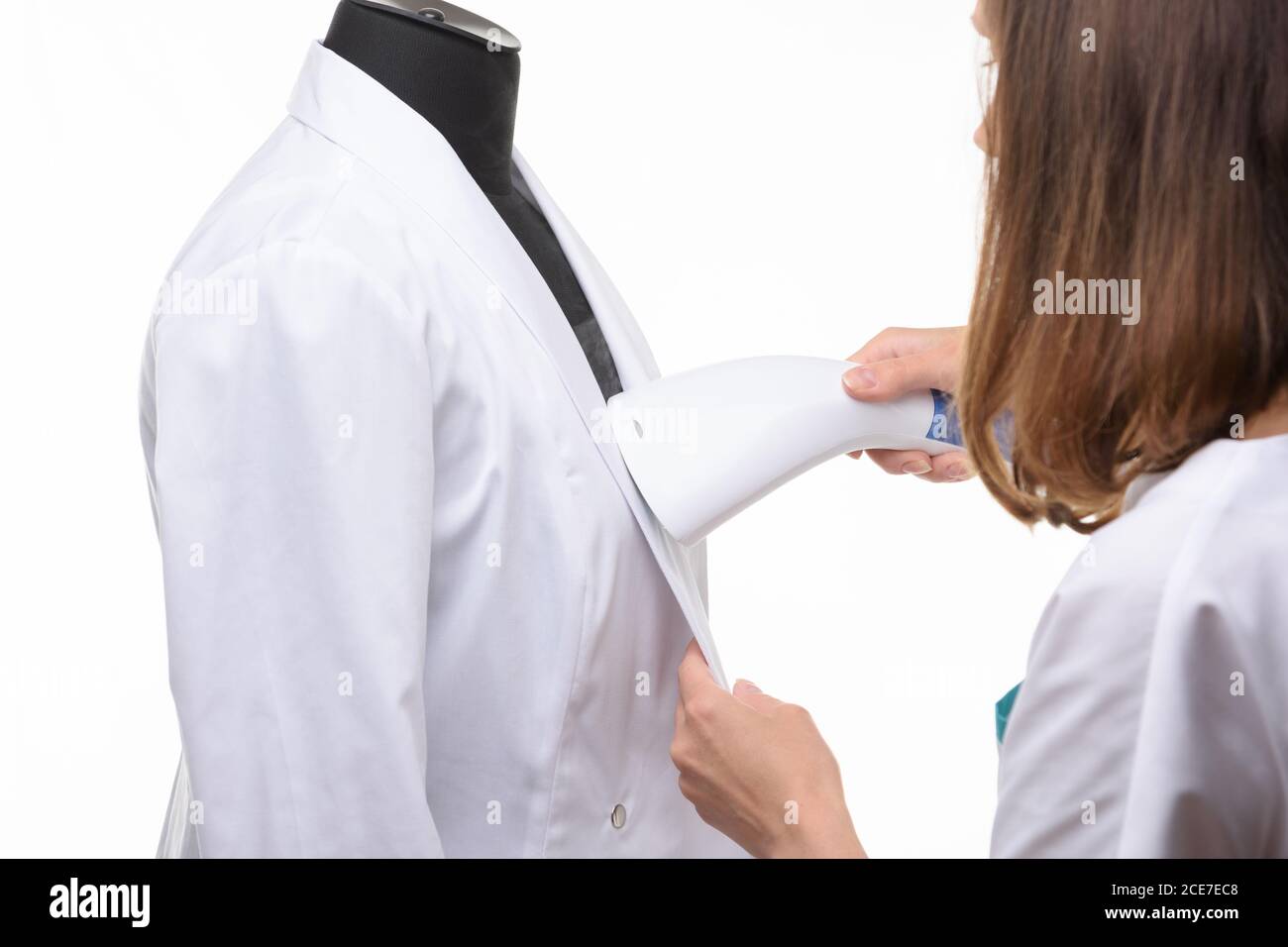 Girl handles medical clothing by steamer on a white background Stock Photo