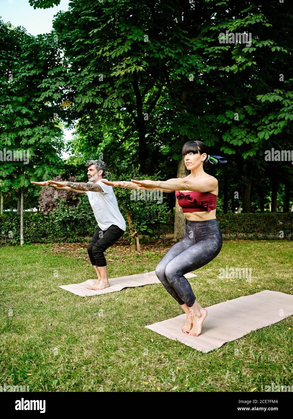 Happy african american plus size woman practicing yoga, stretching next to  swimming pool in garden from Pikwizard