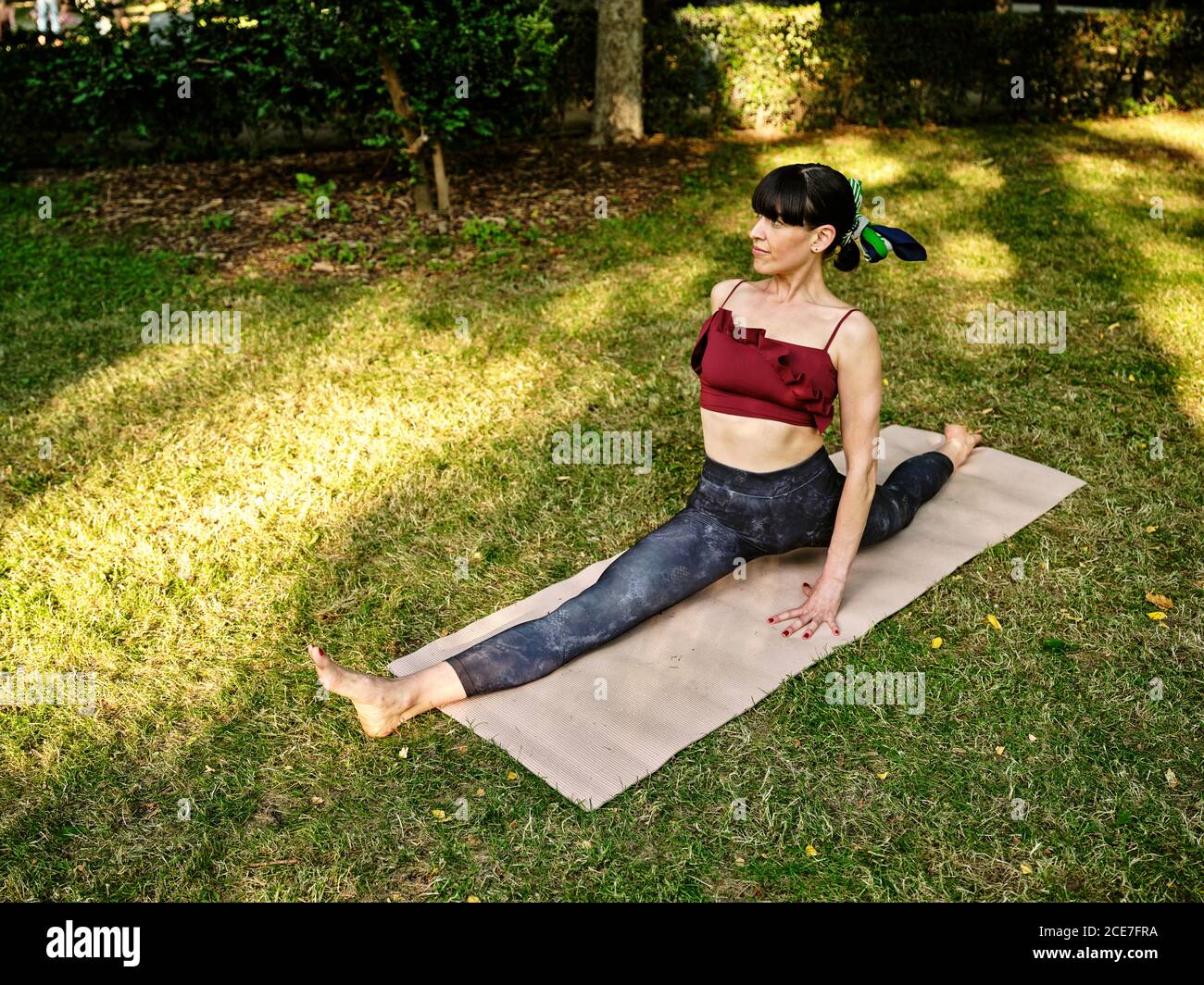 Full body of flexible female yoga trainer performing splits or Monkey