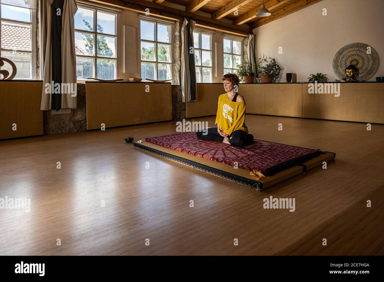Calm female in sportswear sitting on mat in spacious studio and practicing yoga in Padmasana meditation Stock Photo