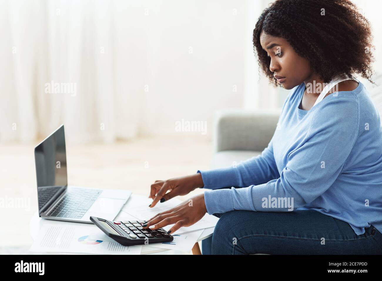 Black woman using calculator and pc at home Stock Photo - Alamy