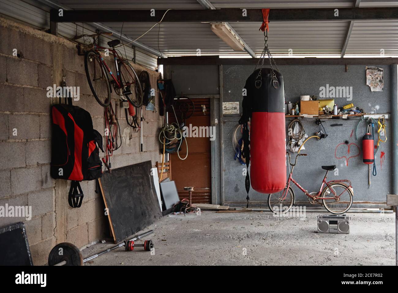 Interior of shabby country garage gym with boxing bag bicycles and sports  equipment placed on concrete floor near old fashioned boombox Stock Photo -  Alamy