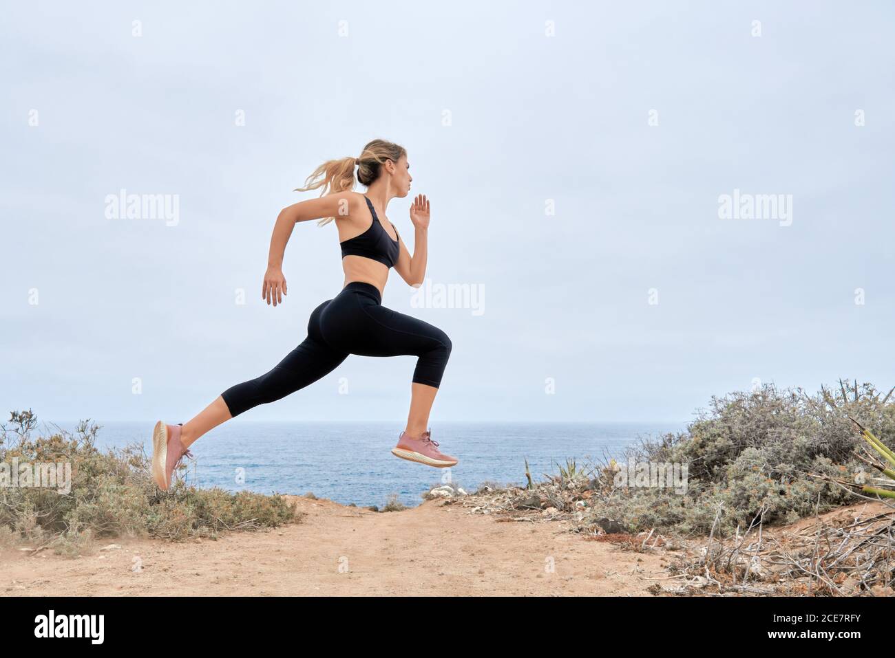 Low angle side view of young fit female in sports bra and leggings running  fast along sandy seashore during fitness workout in summer day Stock Photo  - Alamy