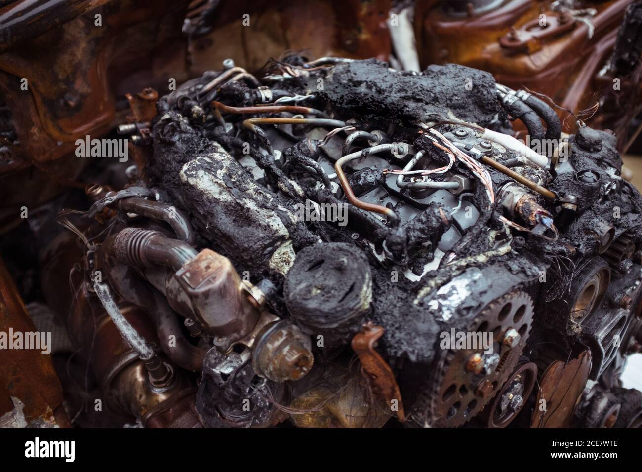 From above of ruined auto hood with burned radiator tank and motor near demolished tire with metal wheel rim in workshop Stock Photo