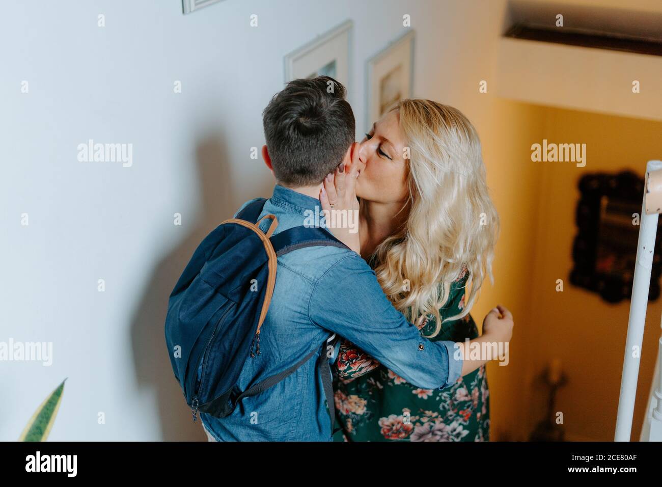 Content mother gently kissing teenage son with school backpack while  hugging together on steps in cozy modern house Stock Photo - Alamy