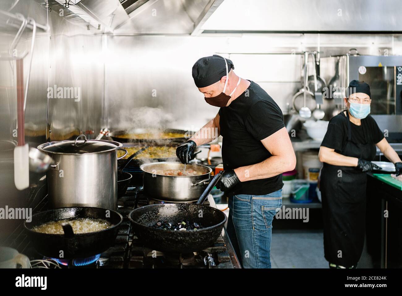Serious male cook wearing apron respirator and latex gloves preparing