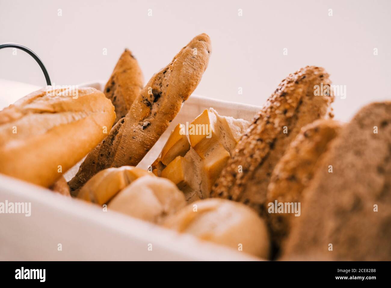 Fresh assorted cut bread and buns served in tray on white table during breakfast Stock Photo