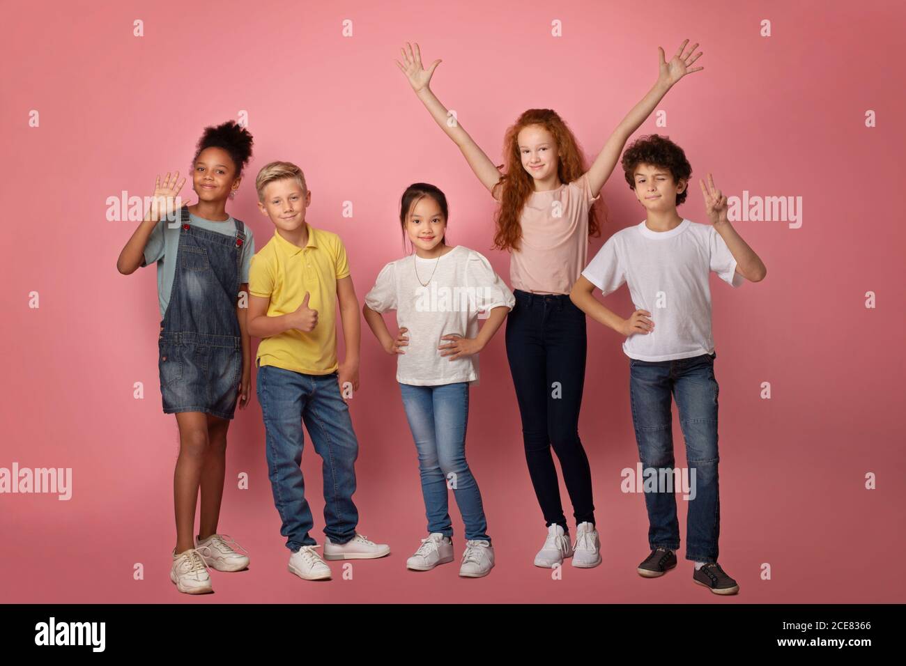 Full length portrait of happy diverse schoolkids making different gestures on pink background Stock Photo