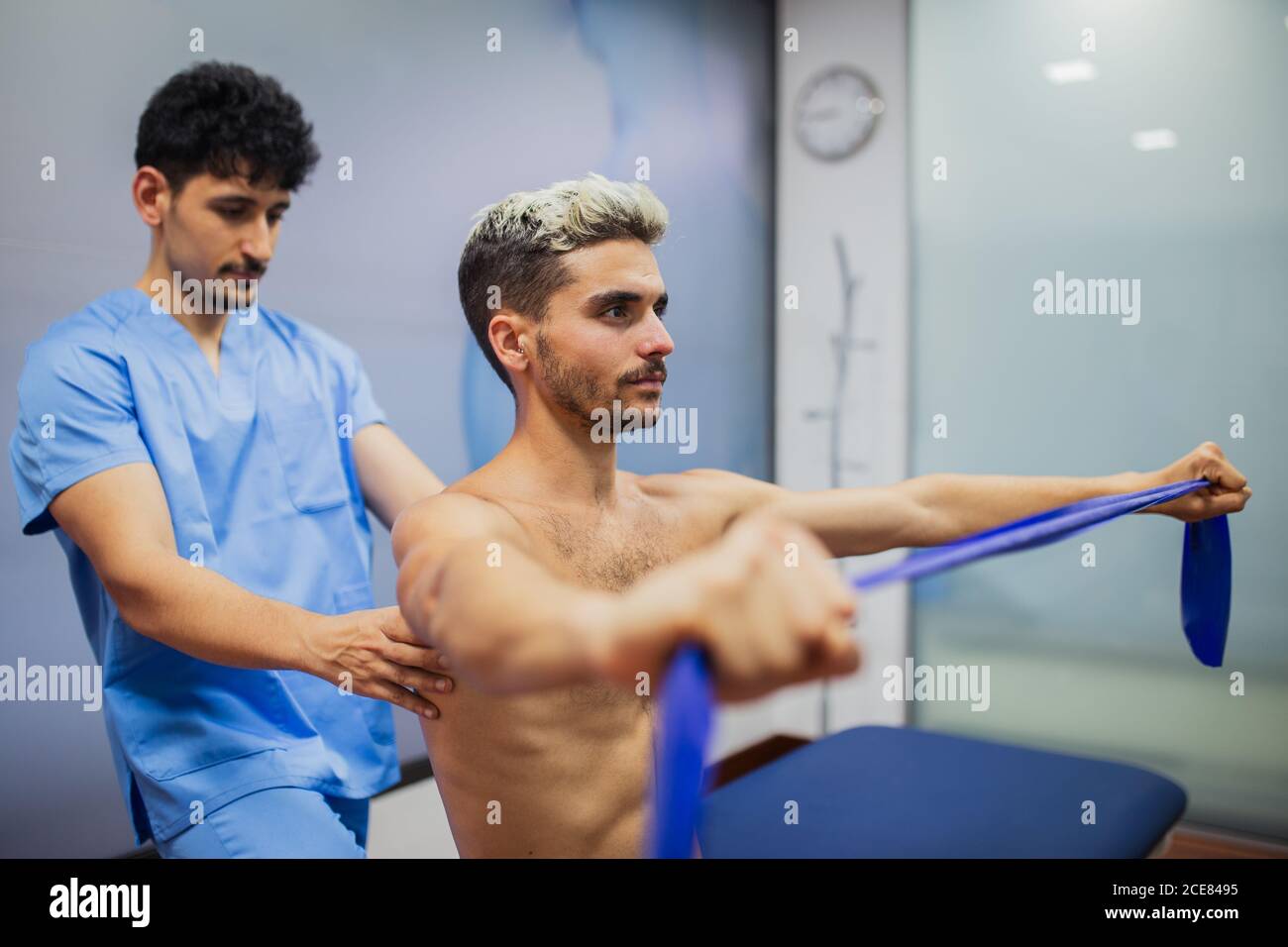 Sports medicine doctor checking up back of sportive man with dyed hair