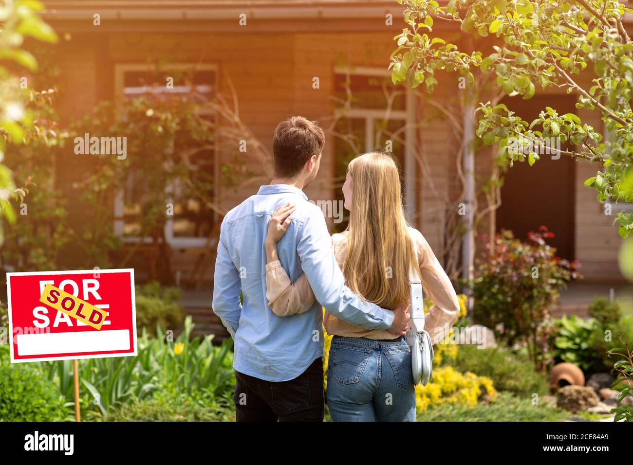 Back view of young couple standing in front yard of their new house, outside Stock Photo