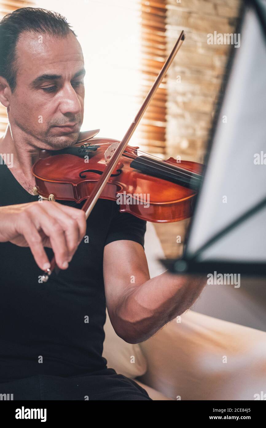 Talented focused Hispanic male violinist playing violin during
