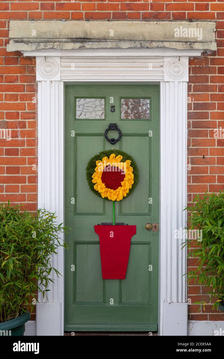A cottage door with a knitted sunflower hanging on it Stock Photo