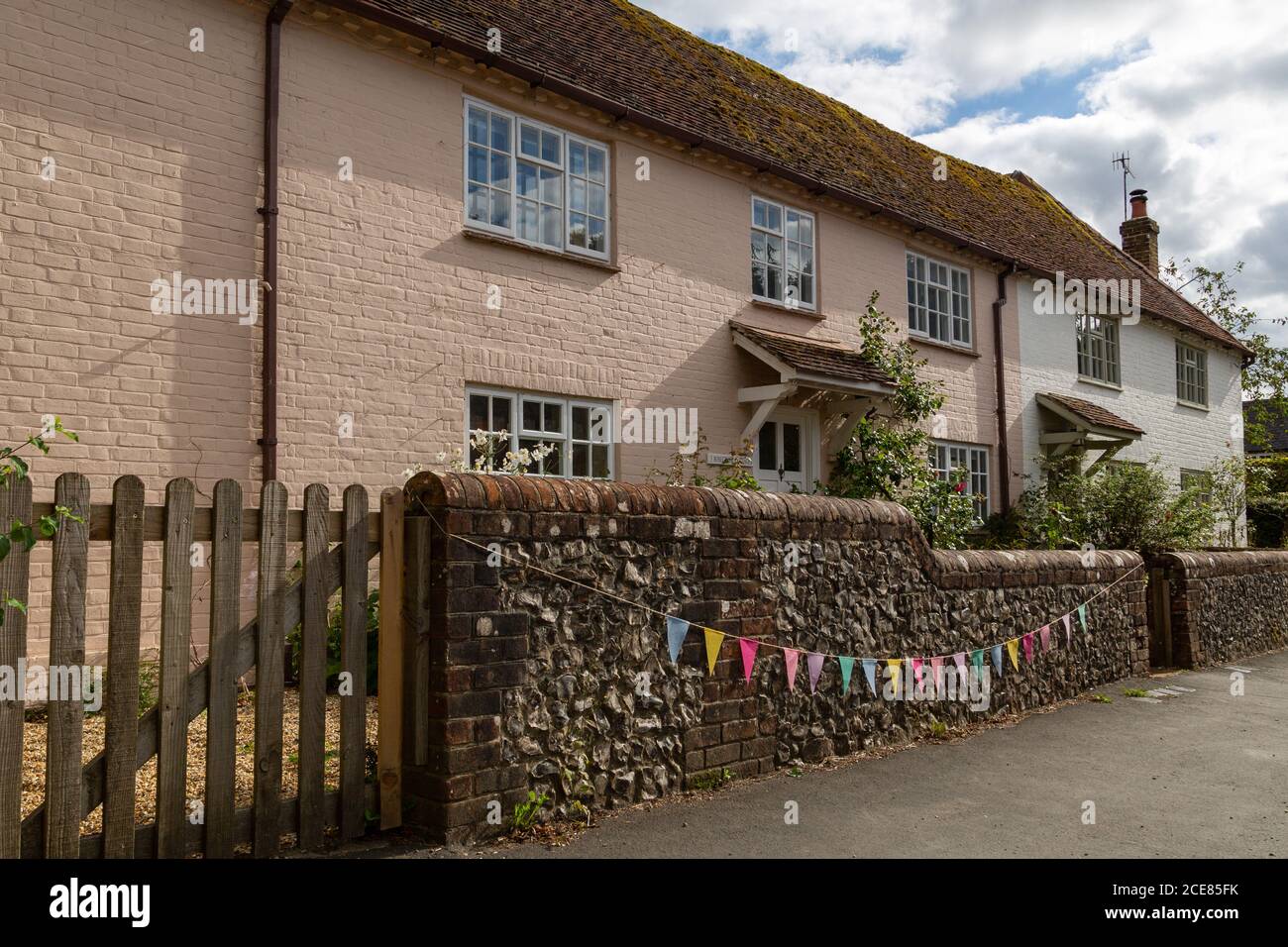 An English Country cottage with bunting hung on the wall outside, Hambledon hampshire, UK Stock Photo