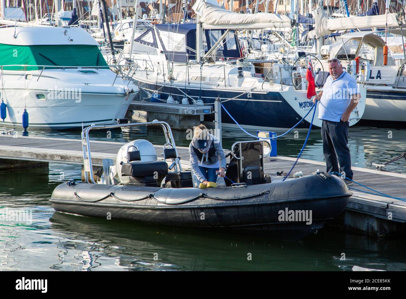 Two people cleaning a rigid inflatable boat after a day at sea Stock