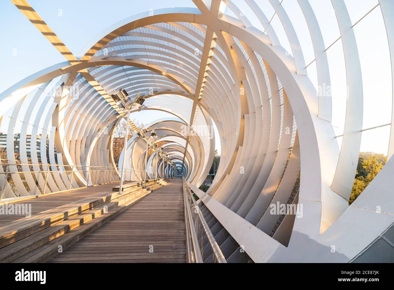 Perspective inside passage of helical cone shaped Arganzuela bridge with internal metal intertwined spirals crossing diagonally in sunset time in Madrid Stock Photo