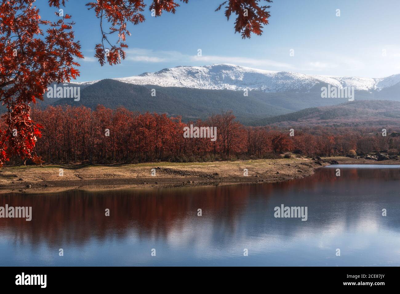 Shore of calm river against snowy autumn mountain ridge and cloudy sky in nature Stock Photo