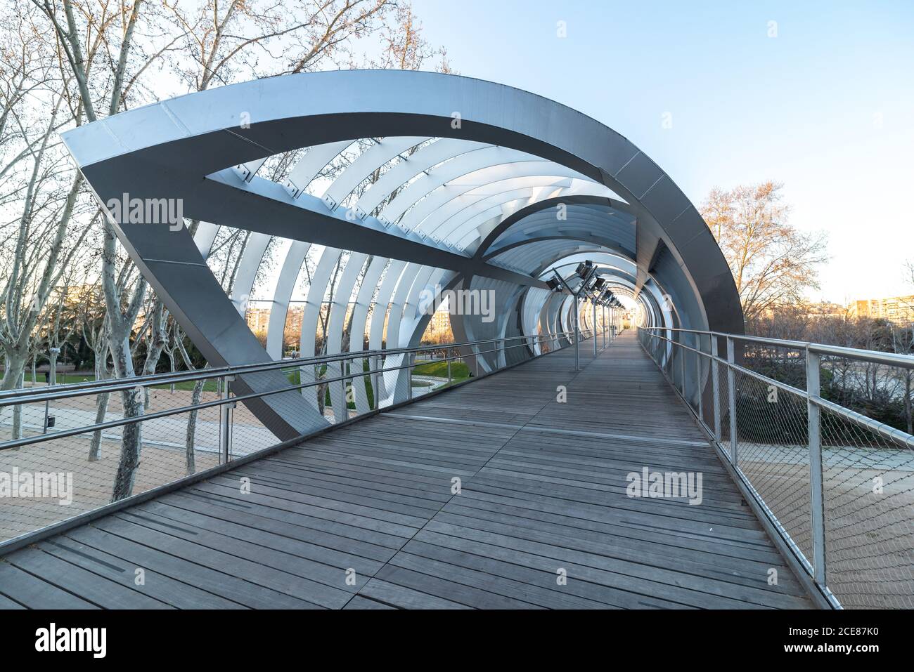 Perspective inside passage of helical cone shaped Arganzuela bridge with internal metal intertwined spirals crossing diagonally in sunset time in Madrid Stock Photo