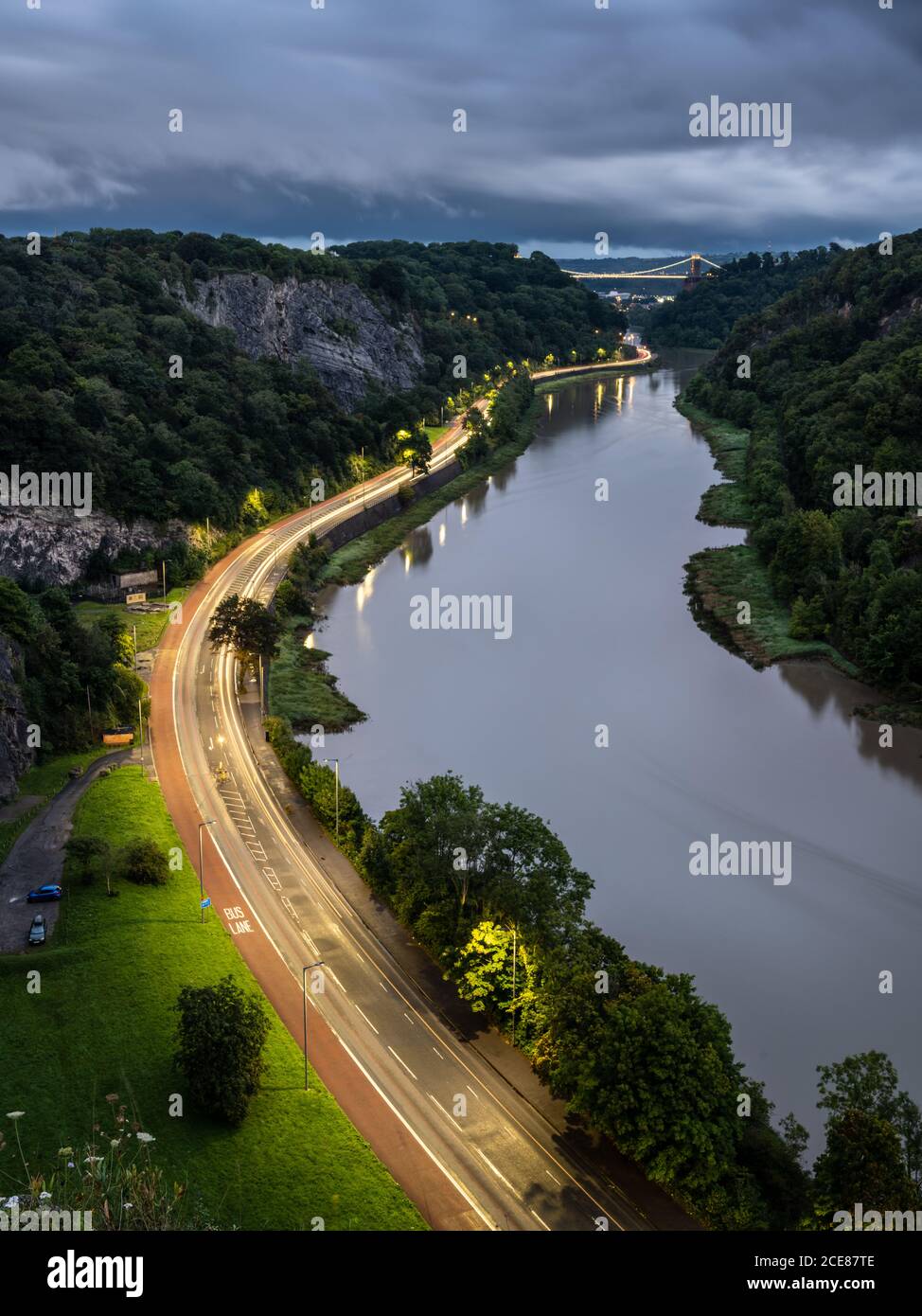 Traffic leaves trails of light at dusk on the A4 Portway Road under the Clifton Suspension Bridge in Bristol's River Avon Gorge. Stock Photo