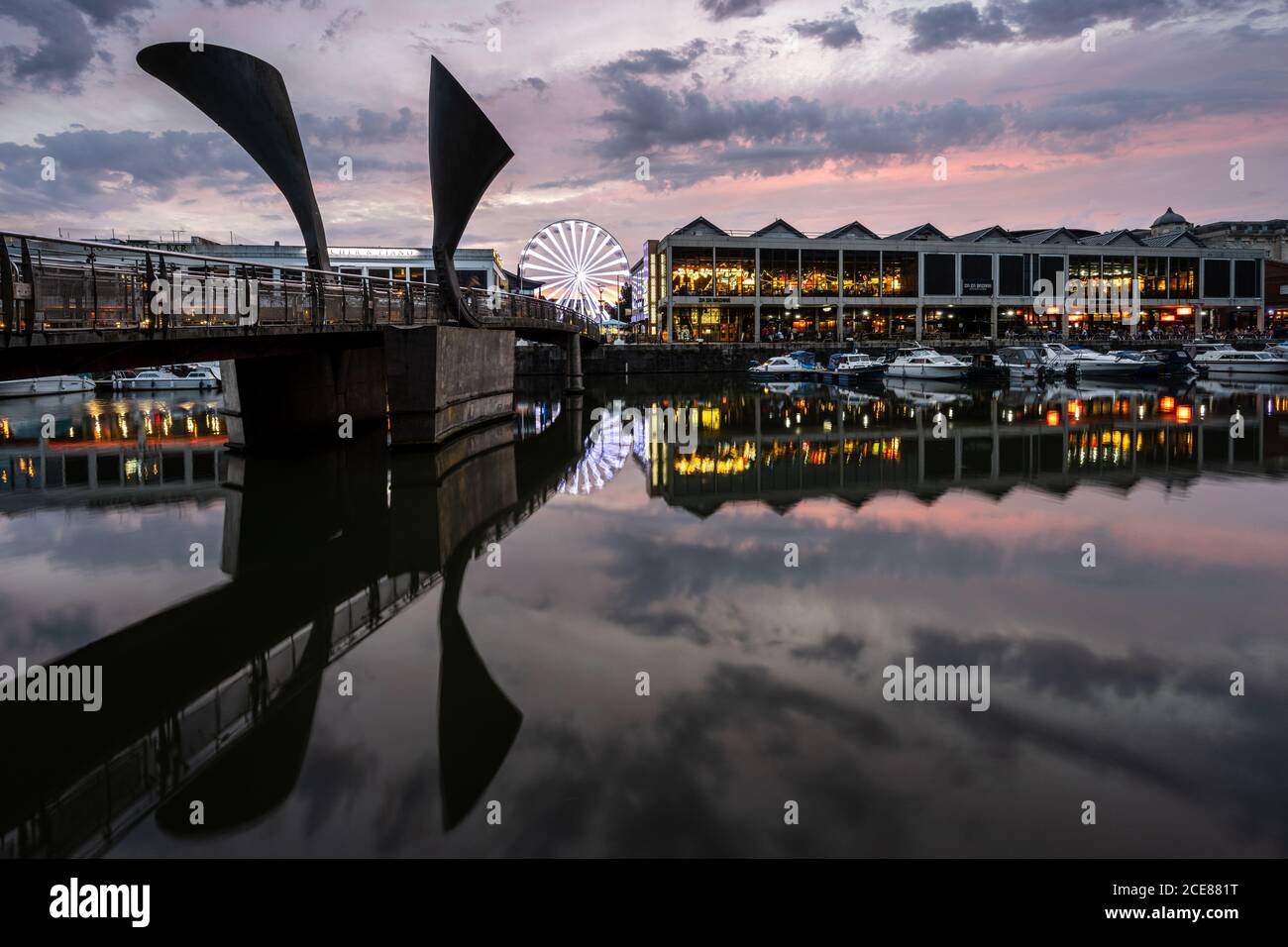 Sunset lights up the sky above Pero's Bridge and Anchor Square on Bristol's regenerated post-industrial Harbourside. Stock Photo