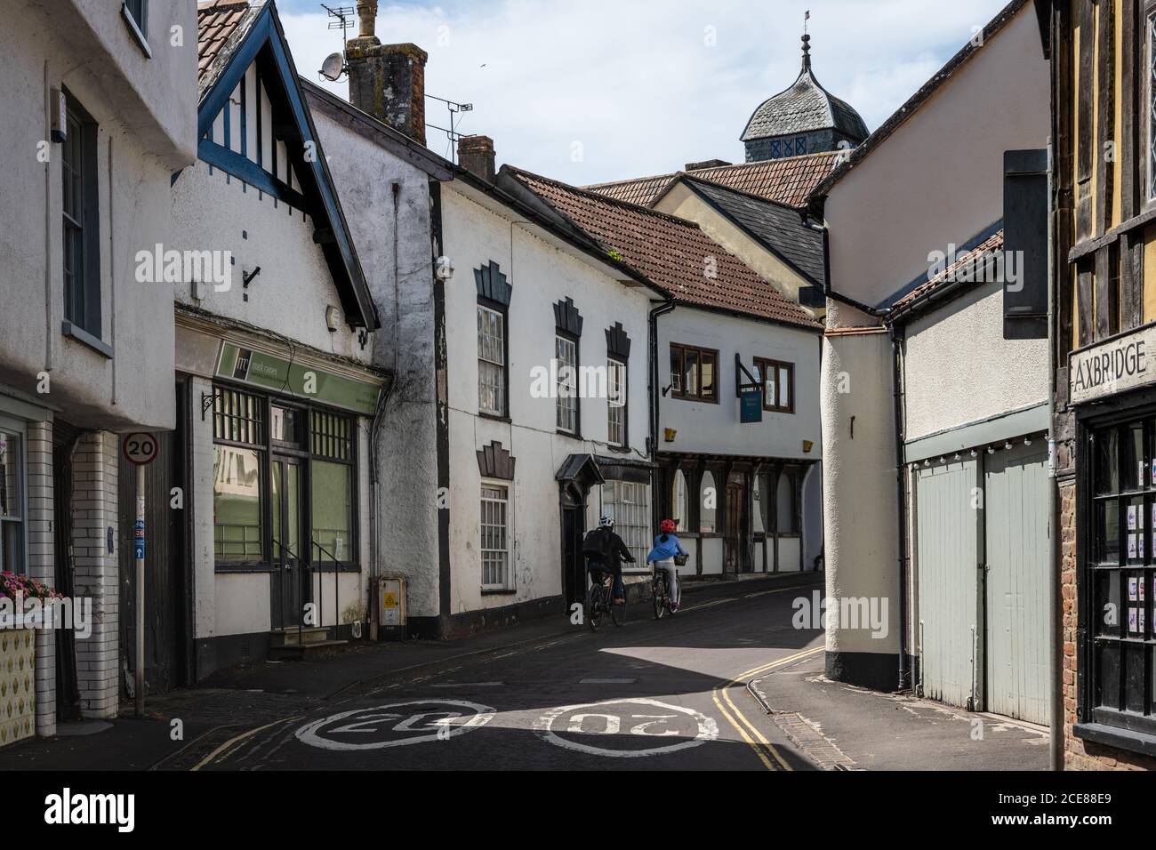 Two cyclists ride past traditional shops and old houses on a National ...