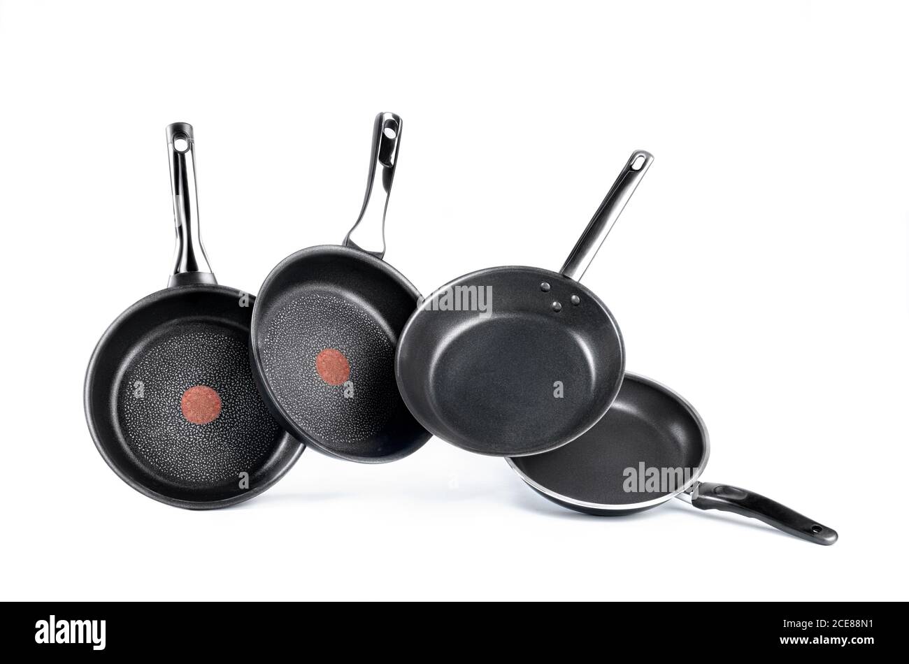 Modern frying pans with non stick coating placed in row above ground in studio Stock Photo