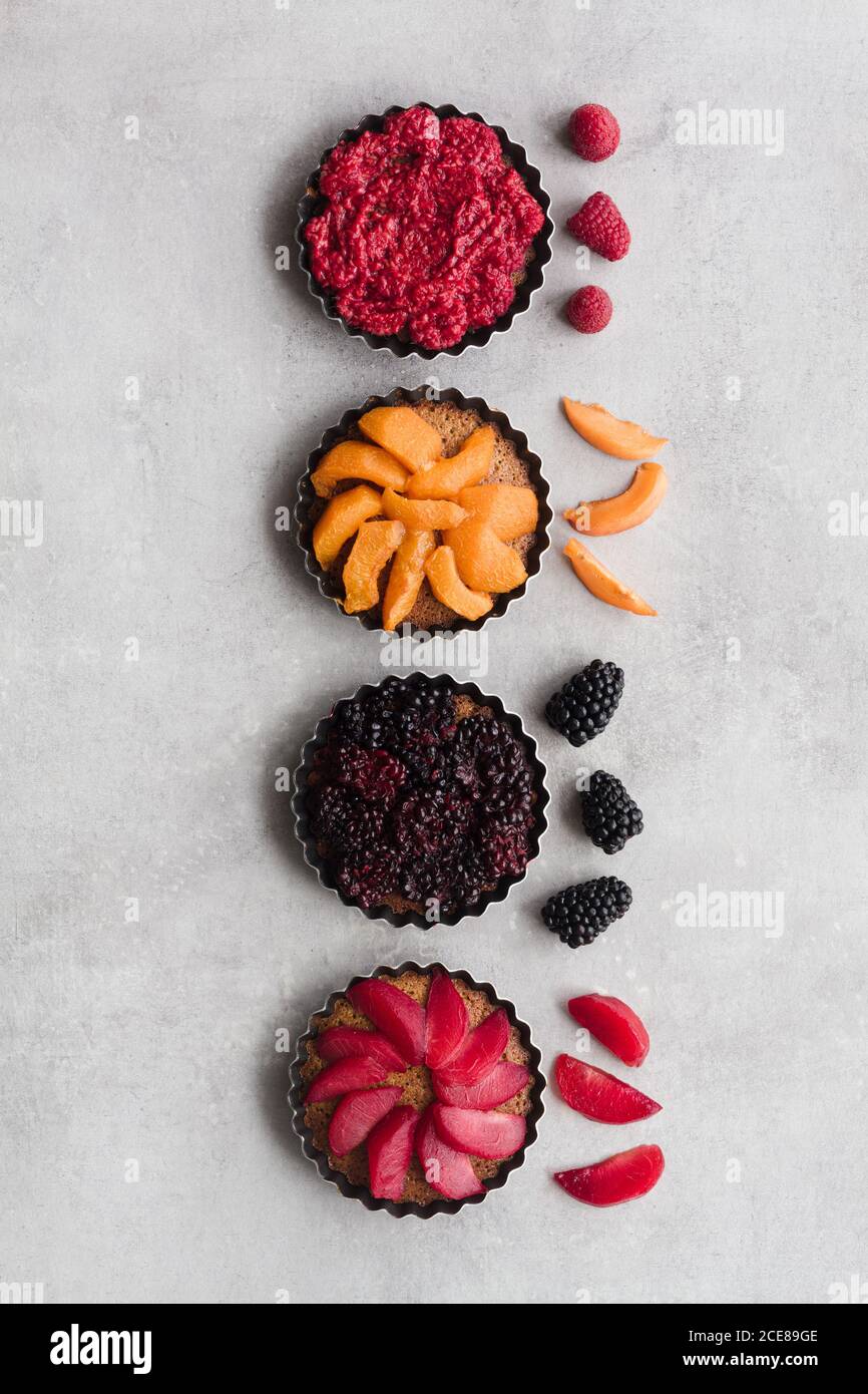 Top view of palatable pies with various ripe fruits and berries arranged in line on table Stock Photo