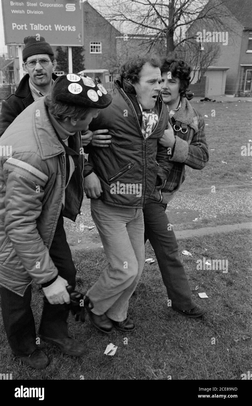 An injured miner is helped away by fellow pickets at Port Talbot Steelworks, South Wales, during the miners' strike of 1984 Stock Photo
