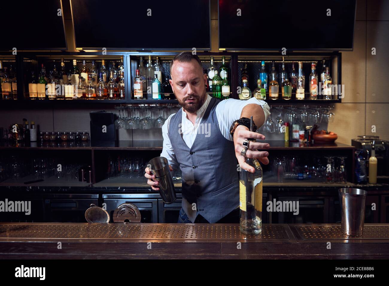 Professional young bartender holding bottle while preparing a cocktail