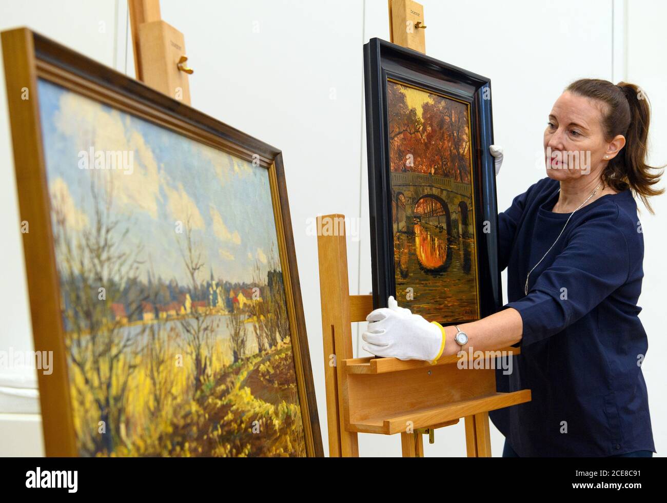 31 August 2020, Brandenburg, Potsdam: Jutta Götzmann, director of the Potsdam Museum - Forum for Art and History, takes the oil painting 'Kellertorbrücke' (Cellar Gate Bridge) by the Potsdam painter Max Friedrich Koch (1859 - 1930) from the easel after a press conference on the donation of two paintings. The painting was in the possession of a family from Neuss, lay for a long time packed in rubbish bags on a cupboard and was offered on 30.01.2020 in the ZDF programme 'Bares für Rares'. Instead of the hoped-for 300 euros for the oil painting, mother and daughter received 1650 euros from a Wies Stock Photo