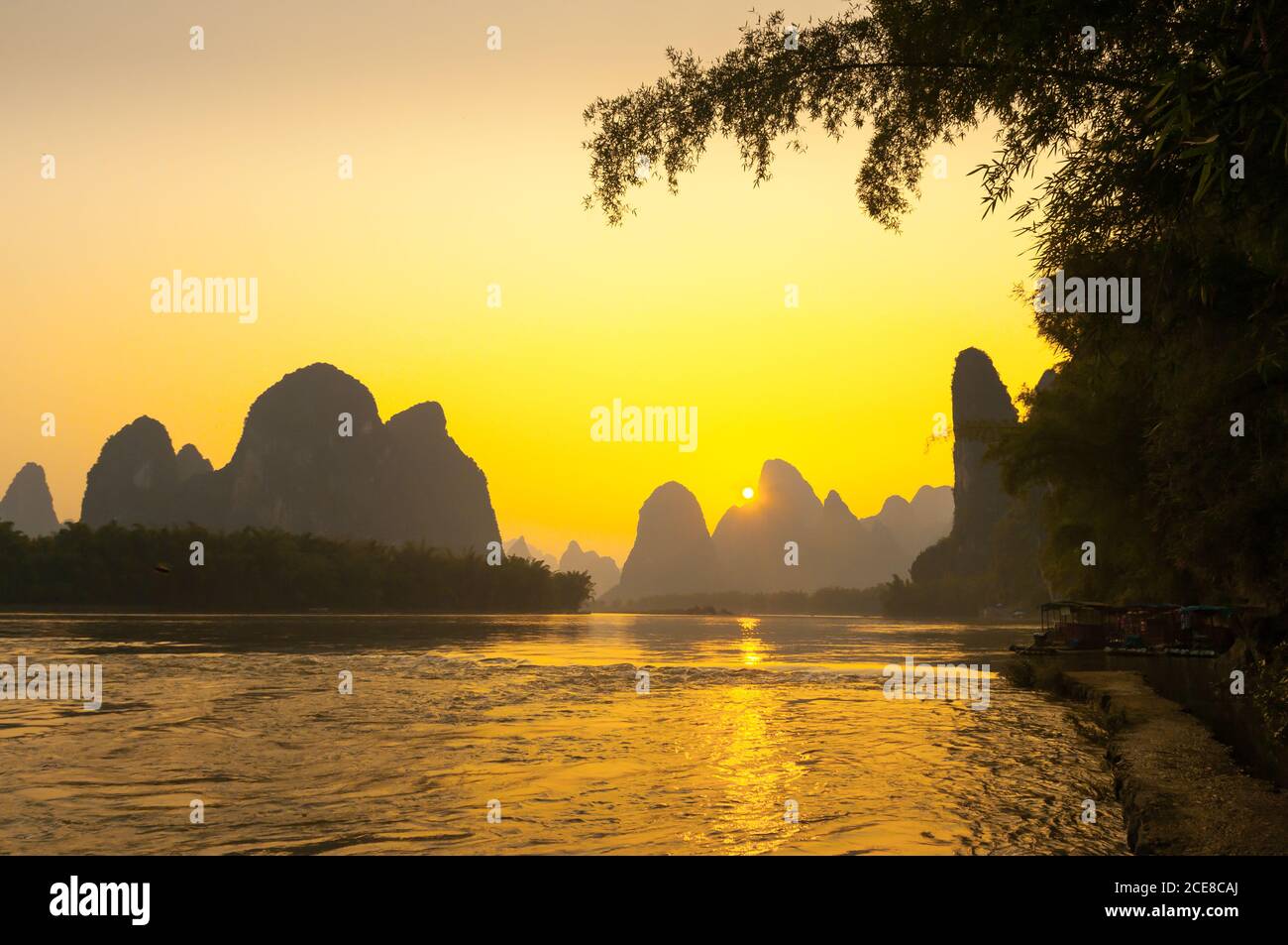 Amazing view of silhouettes of mountains and rippling water during bright sundown in Yangshuo County, China Stock Photo