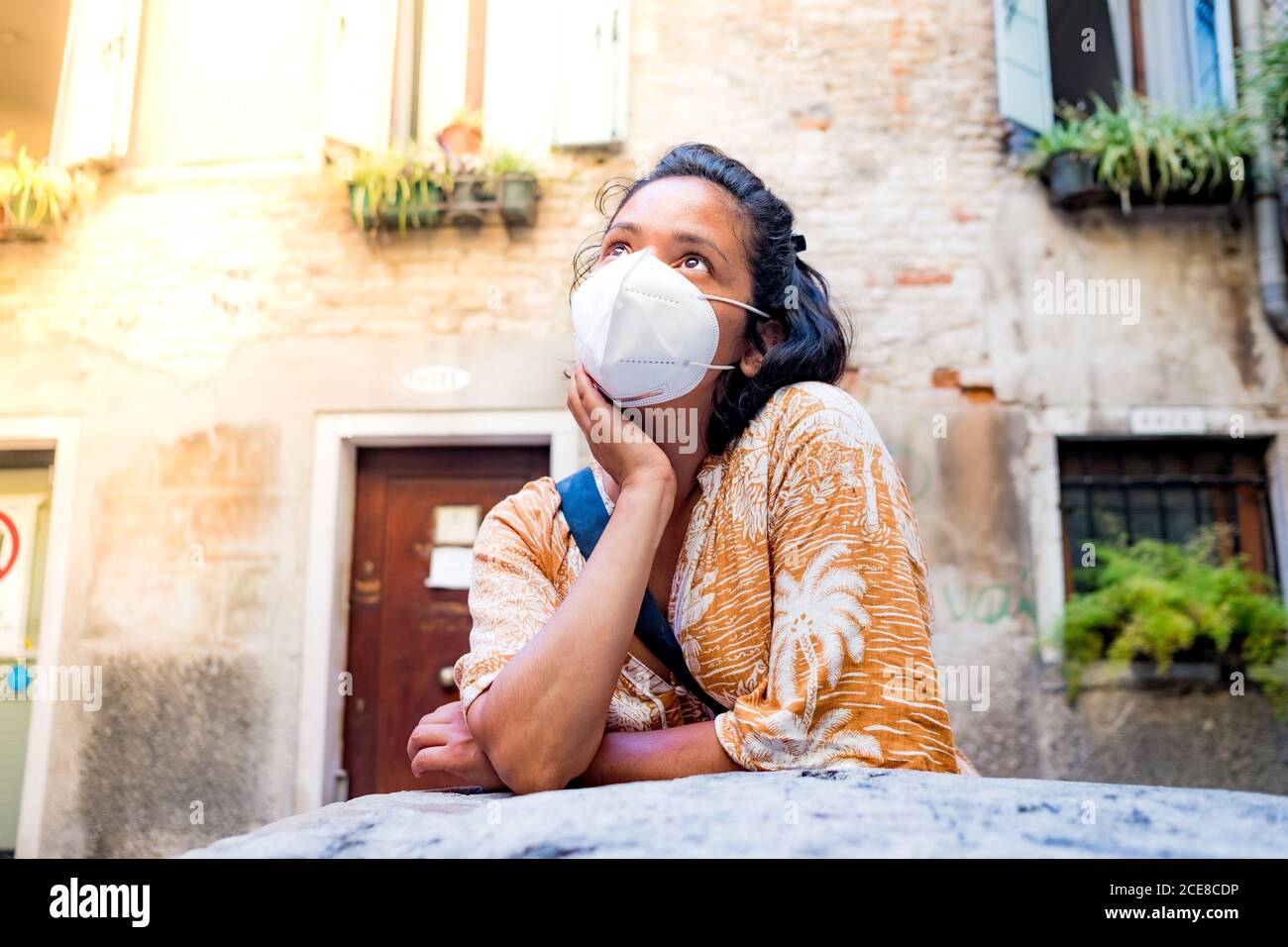 young woman wearing face mask looking up in a street of Venice in Italy. traveling and tourism industry during the corona virus pandemic and covid19 d Stock Photo