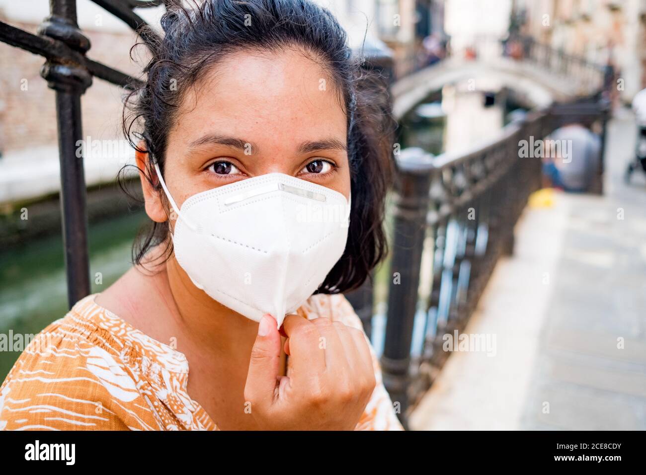 young tourist wearing face mask relaxing in a street of Venice in Italy. traveling and tourism industry during the coronavirus pandemic and covid-19 d Stock Photo