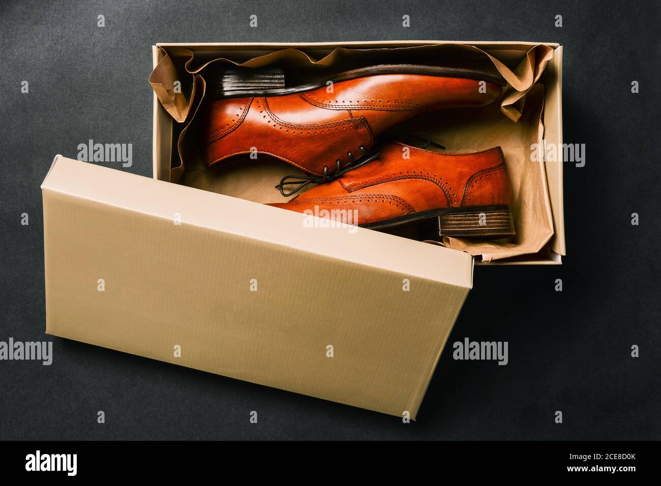 Men shoes in an open box, isolated on a black background. Open Shoe box. New shoes from the store. Brown shoes made of genuine leather. The view from Stock Photo