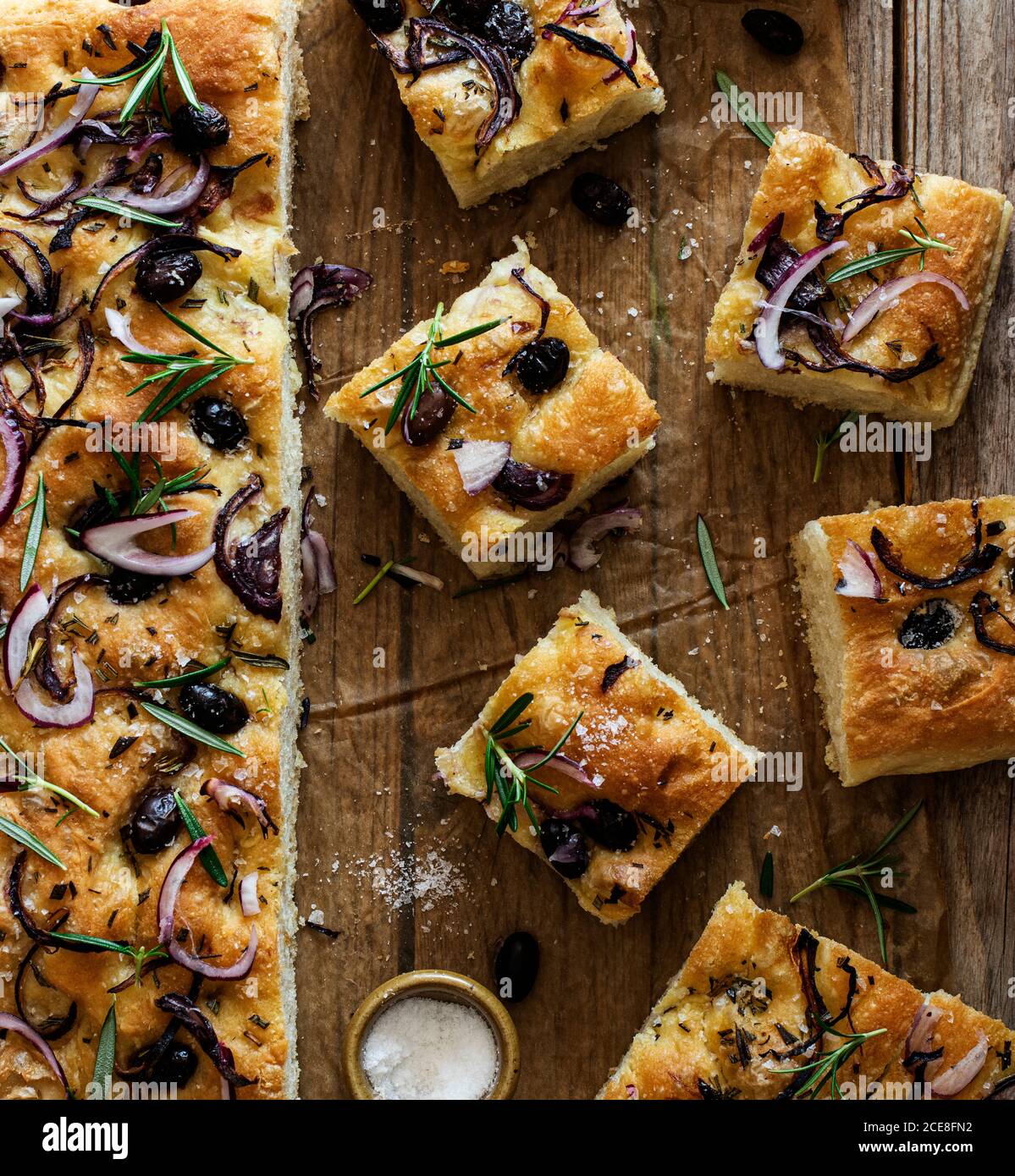 Focaccia with black olives and herbs on wooden table Stock Photo