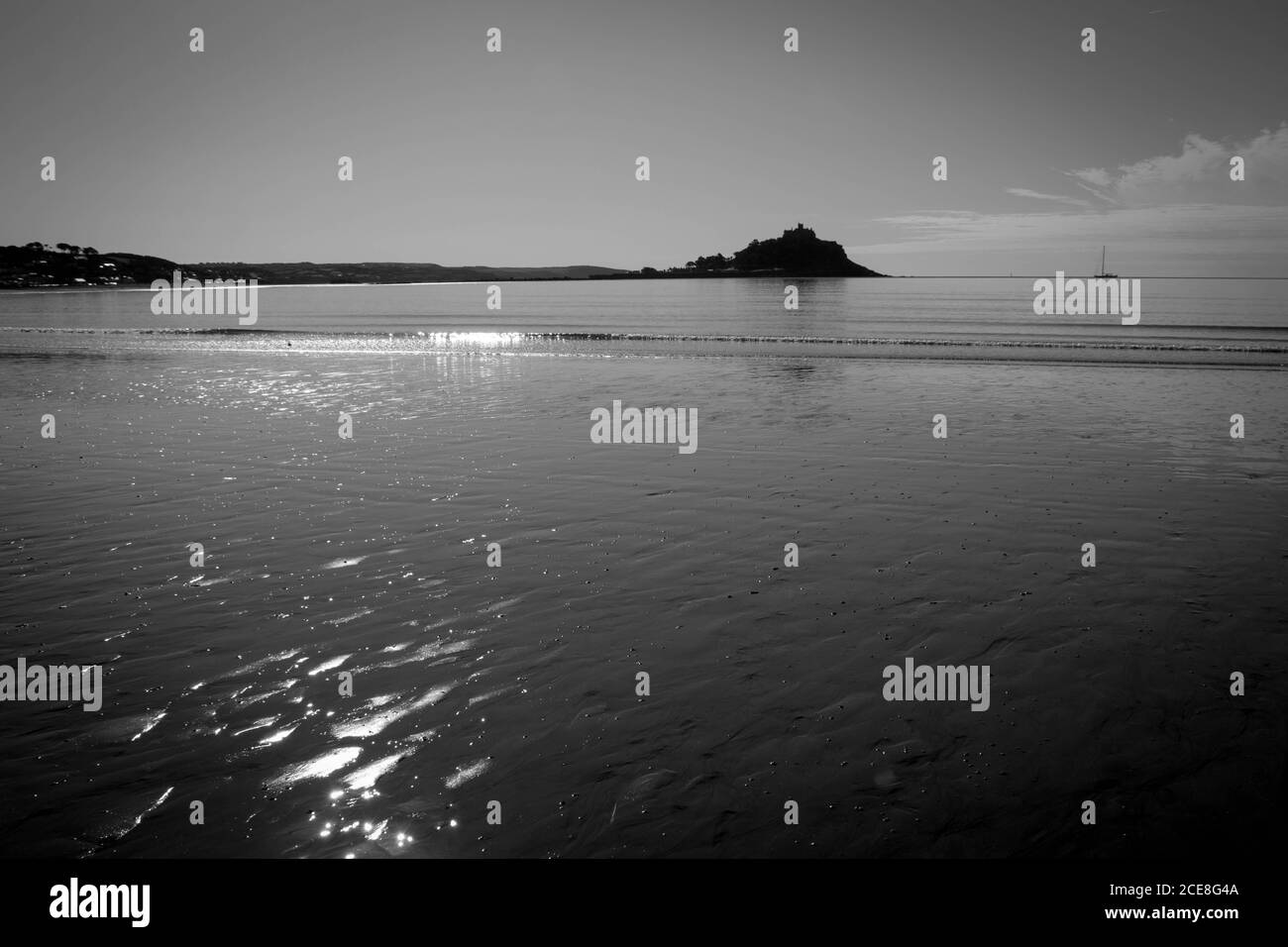 Sun reflecting on smooth beach at low tide with St Michael's Mount in the distance, black and white Stock Photo