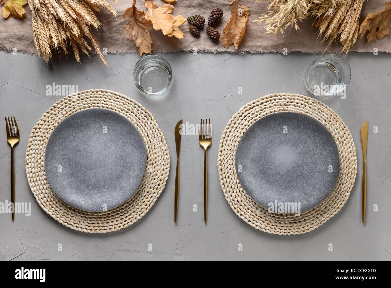 Autumn table setting with dry yellow oak leaves, fall decoration and golden cutlery on grey table. Flat lay, top view. Thankisgiving day Stock Photo