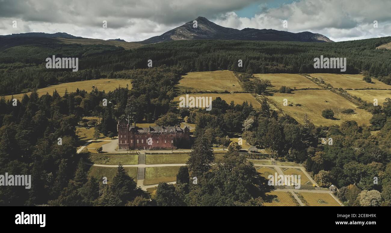 Scotland's landscape aerial shot: mountains, ancient Brodick Castle with Goatfell mount. Epic scenery of Scottish landmarks. Wonderful forests and valleys at summer day wide view Stock Photo