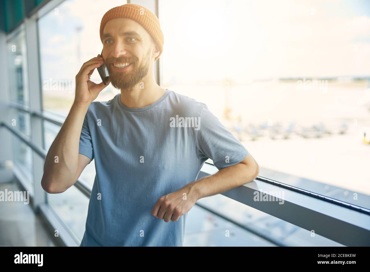 Happy smiling man in orange hat standing in front of glass window Stock ...
