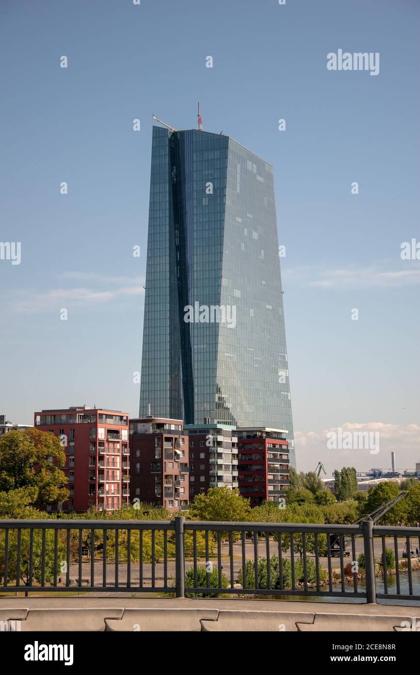 Vertical shot of a tall modern glass building near smaller buildings ...