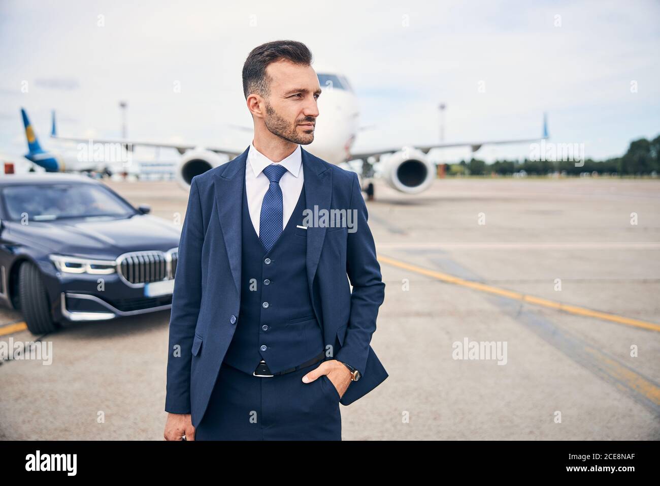 Stylish man in a suit posing next to an airplane Stock Photo Alamy
