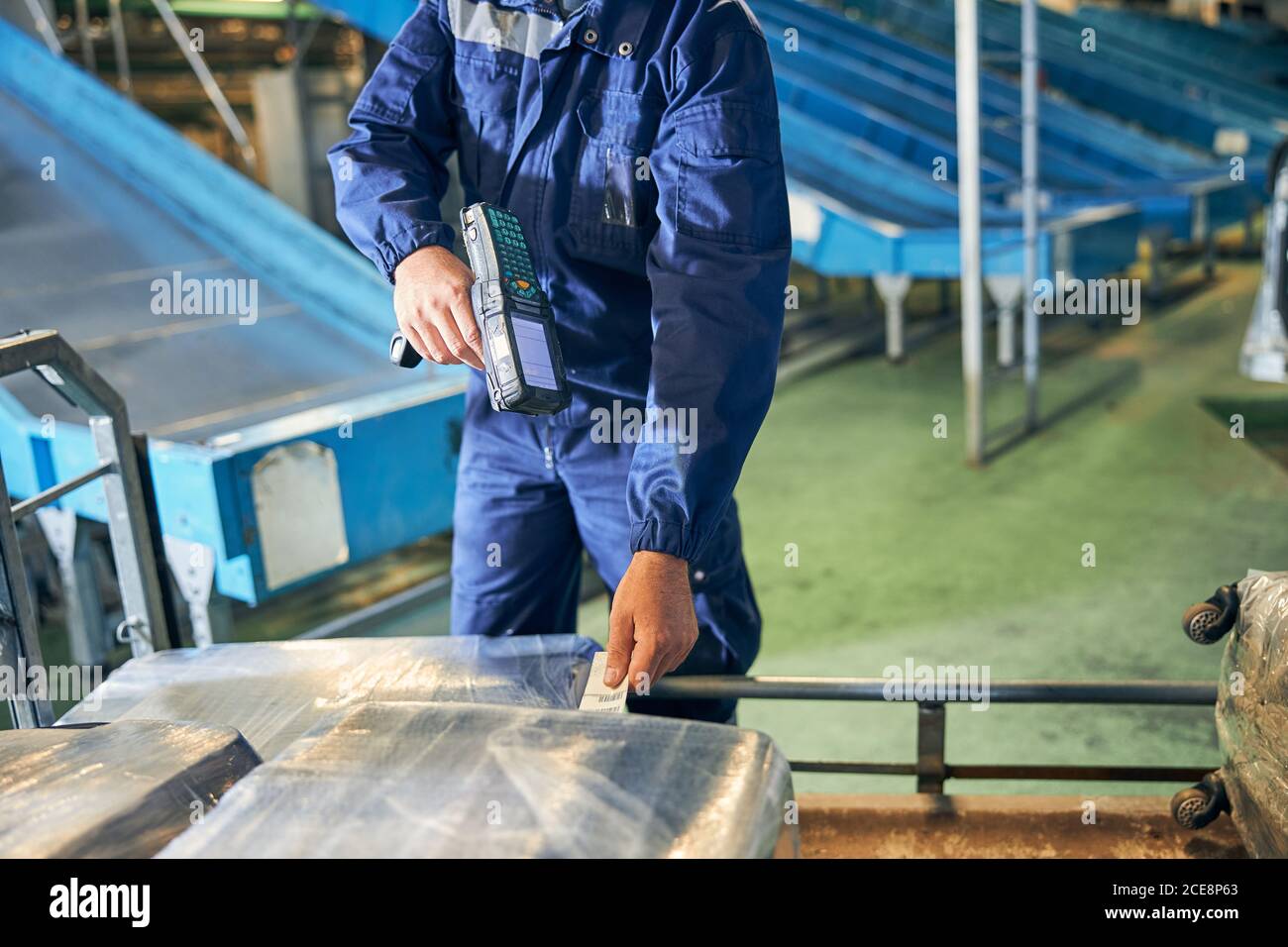 Baggage department worker scanning a luggage tag Stock Photo