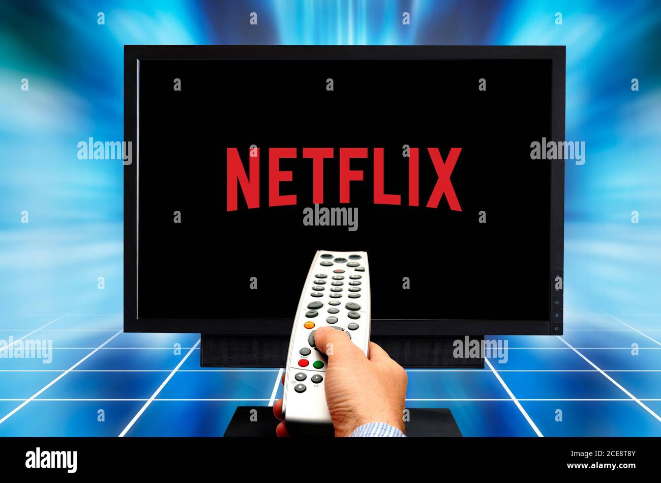 male hand with remote control and Netflix logo on TV screen Stock Photo