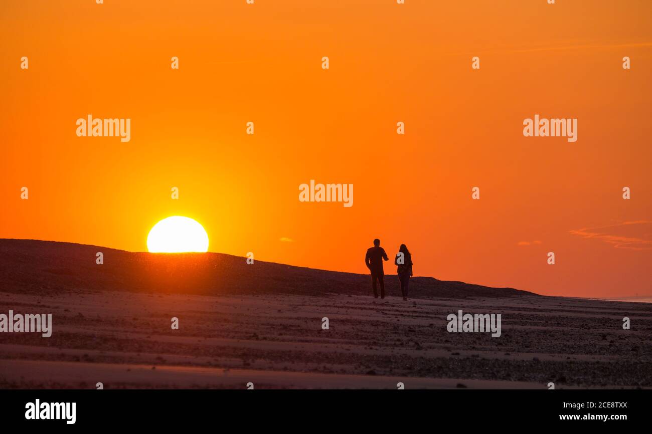 Walking along a beach at sunset. Stock Photo