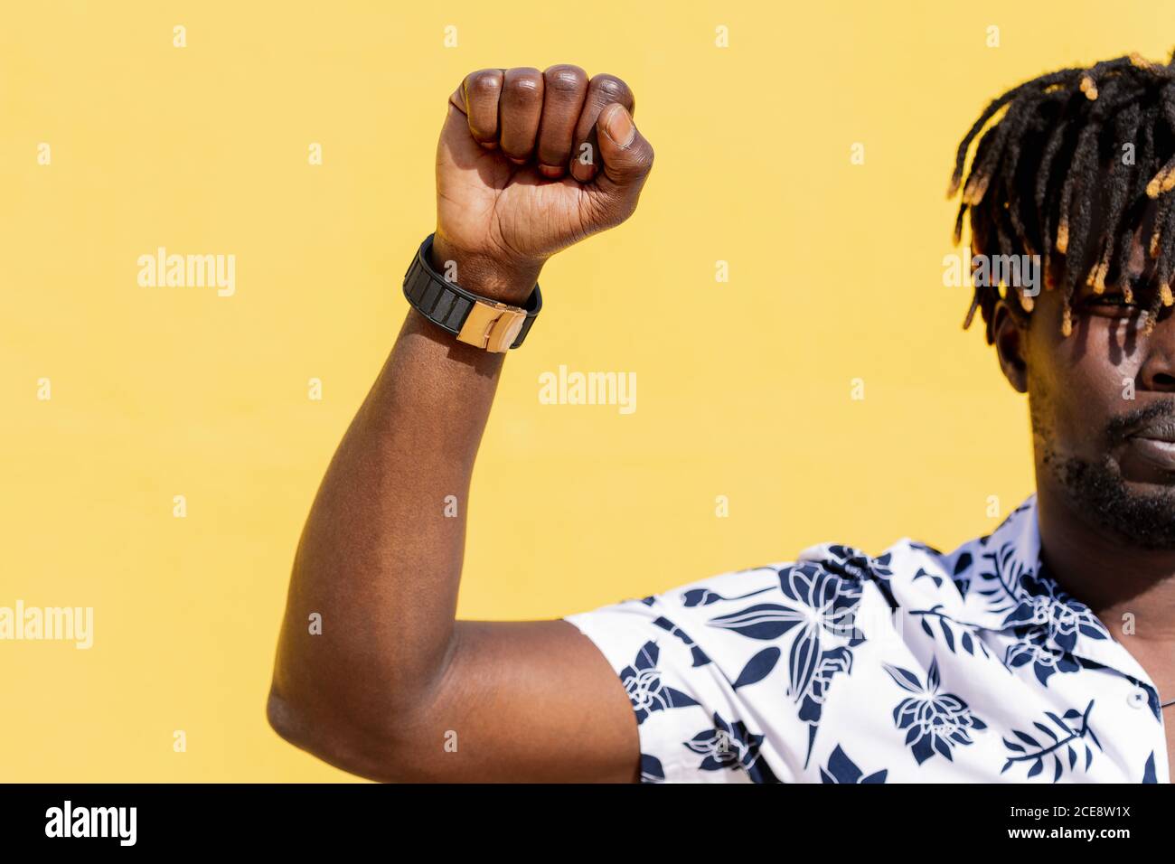 attractive young black man with raised fist on an intense yellow background, concept of human rights struggle and lifestyle, copy space for text Stock Photo