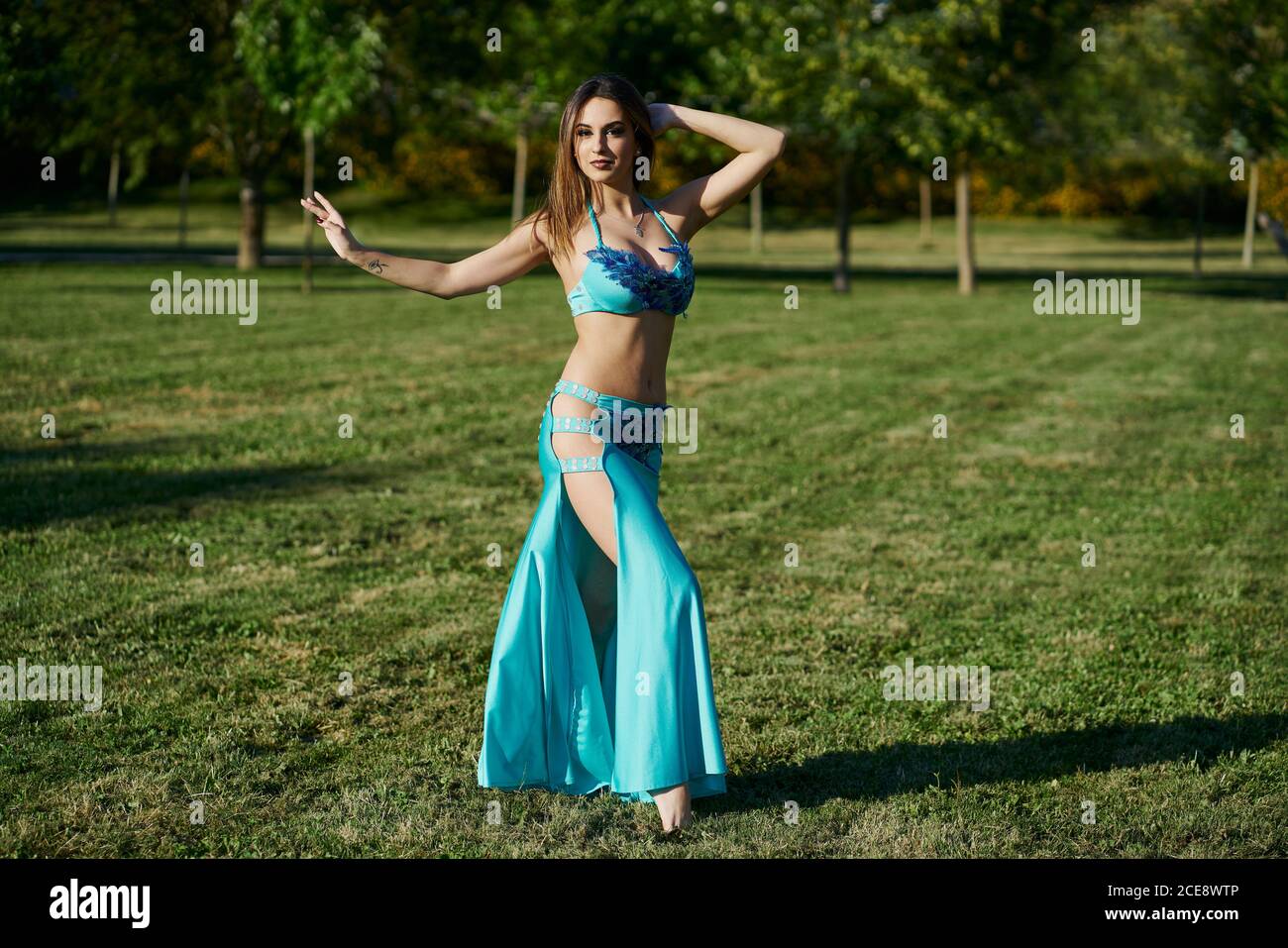 Female belly dancer performing oriental dance while standing in posture and looking at camera Stock Photo