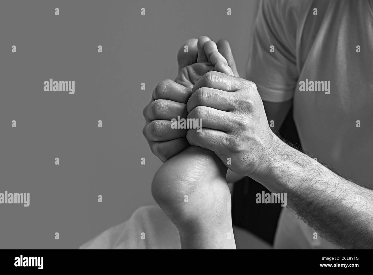 Male masseur doing massage on female foot reflex zone in the spa salon. Stock Photo