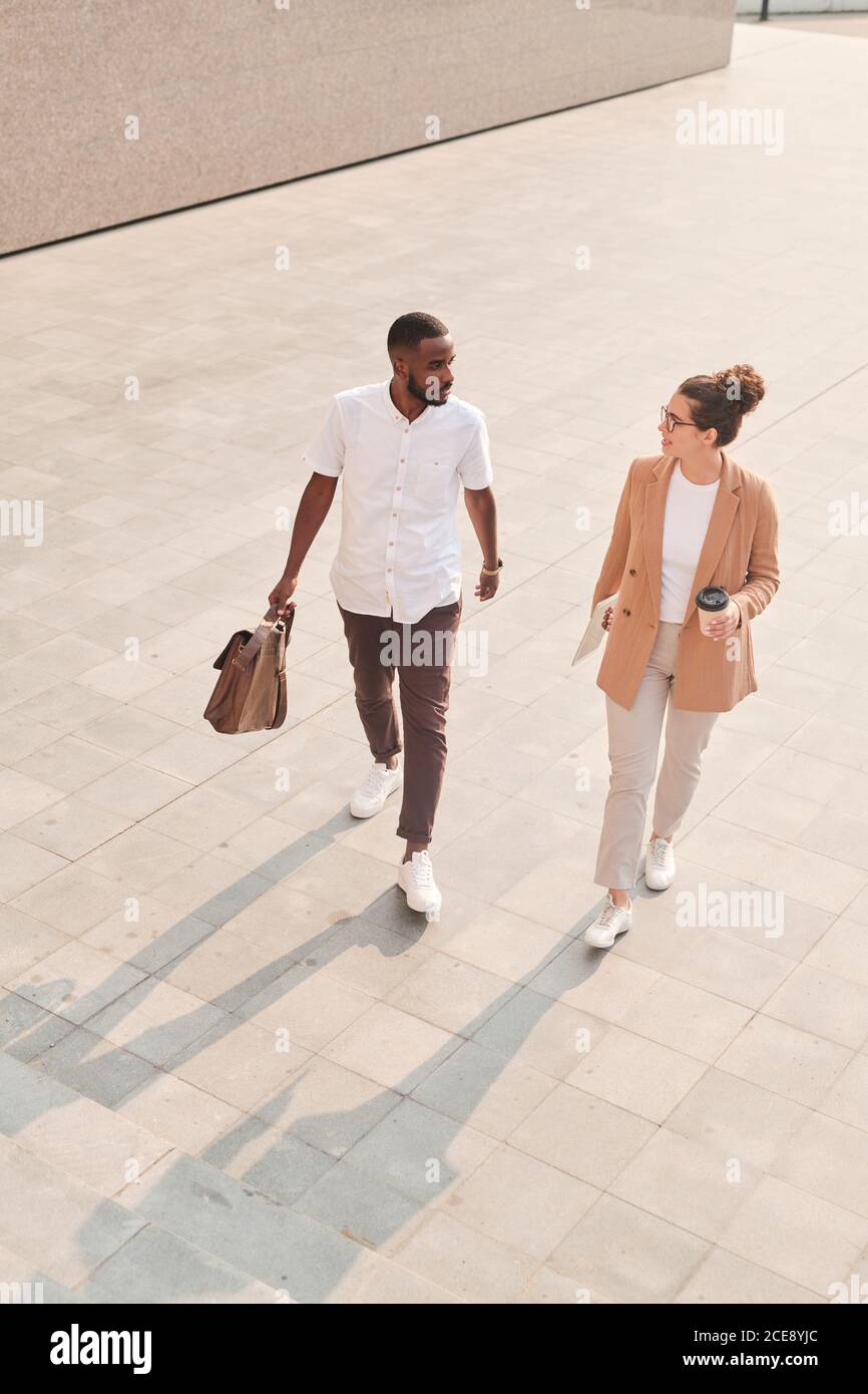 Above view of young multi-ethnic colleagues discussing work issues on move while getting to office Stock Photo