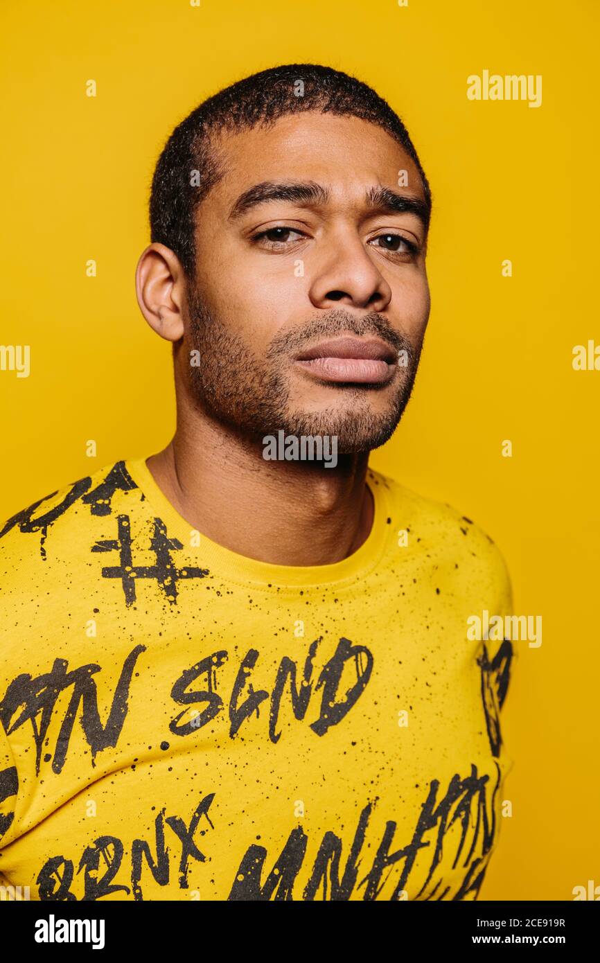 Mixed race young man looking at camera with serious expression over yellow background Stock Photo
