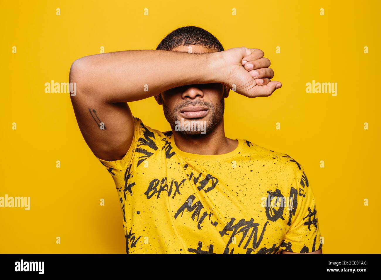 Mixed race young man looking at camera with serious expression over yellow background Stock Photo